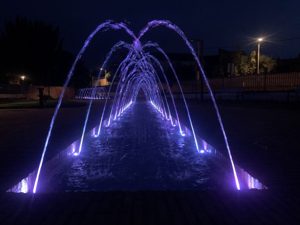 Fuente luminosa en plaza iluminada durante la noche